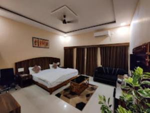 a bedroom with a bed and a couch and a desk at Hotel Aaradhya International Jagdalpur in Jagdalpur