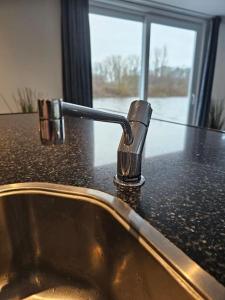 a bathroom sink with a faucet on a counter at Luxe woonboot in de natuur evt met console bootje! in Leeuwarden
