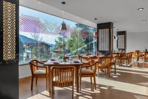 a restaurant with wooden tables and chairs and a large window at Ginger Gangtok in Gangtok