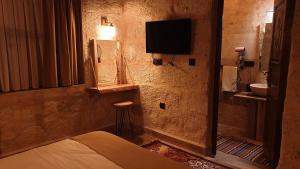 a bedroom with a bed and a television on the wall at Ceran Stone House in Nevsehir