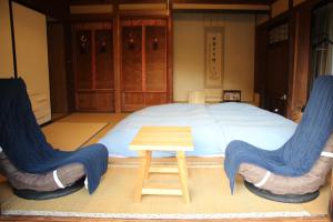 a bedroom with a bed with two chairs and a table at すさのわ in Izumo