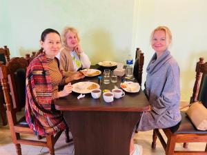 trois femmes assises à une table mangeant de la nourriture dans l'établissement The Lumbini Hotel, à Rummindei