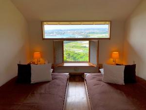 a bedroom with two beds and a large window at Kaiza in Nanjo