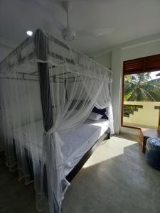a bed with a canopy in a room with a window at cric villa in Galle