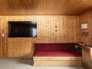a room with a bench with a tv on a wooden wall at Ferienhaus Alpenflora in Mellau +4 photos