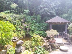 a garden with a gazebo and a pond at Star House in Jeju