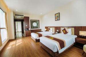 Móng CáiにあるLuxury6 Hotelのベッド2台とデスクが備わるホテルルームです。