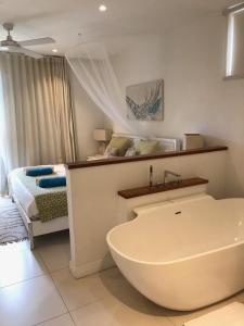 リヴィエール・ノワールにある2 bedrooms charming apartment, West Island Resortのバスルーム(バスタブ付)、ベッド1台が備わります。