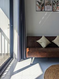 - un canapé brun dans une pièce avec fenêtre dans l'établissement A cozy full service Osimi Apart- hosted by Minh Hai Resort, à Phú Mỹ