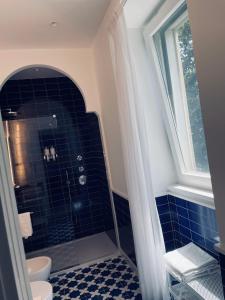 een badkamer met een blauwe betegelde douche en een raam bij Casa Torre a Sorrento con parcheggio gratuito in Sorrento