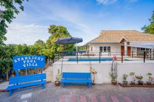 a house with two blue benches and an umbrella at สตาร์ไลท์ พูลวิลล่า ชะอำ หัวหิน in Ban Huai Sai Tai