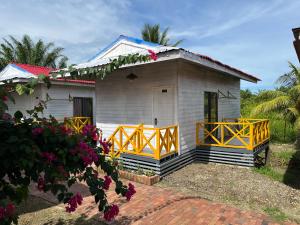 a small white house with a yellow gate in front of it at Coconut Garden Resort 椰苑星辰 in Semporna