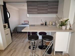 a kitchen with two bar stools and a kitchen with a bed at spacieux studio dans le Beaujolais in Saint-Georges-de-Reneins