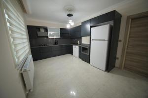 a kitchen with a white refrigerator and black cabinets at GREEN PEARL DELUX APART in Korgan