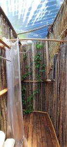 a wooden deck with a curtain and a plant at MALOCA - Chalés Rústicos in Ilha de Boipeba