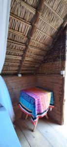 a room with a table in a straw roof at MALOCA - Chalés Rústicos in Ilha de Boipeba