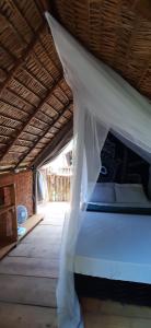 un letto bianco in una camera con soffitto di MALOCA - Chalés Rústicos a Ilha de Boipeba