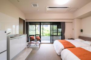 una camera d'albergo con due letti e una cucina di Arbor house a Kagoshima