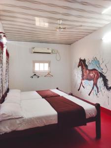 a bedroom with a bed with a painting of a horse on the wall at Achayans Homestay Mararikulam in Mararikulam