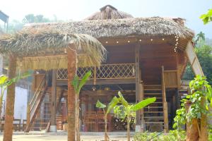 uma cabana com um telhado de palha e algumas árvores em HÀ GIANG WOODEN HOUSE em Ha Giang