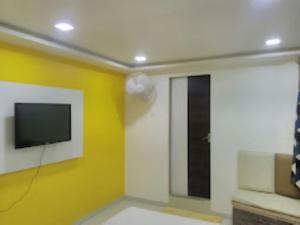 een kamer met een tv en een gele muur bij HOTEL SAIPRASAD LODGE Solapur in Solapur