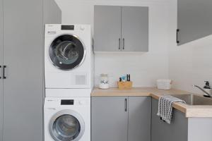 a kitchen with two washing machines and a sink at The Elements l Earth l 4 Stunning Apartments each with Private Outdoor Dining l Walk to the Beach l Pet Family and Event Friendly l Wifi l Netflix l Outdoor Shower l Communal BBQ Pavilion and Lawn Area l in Christies Beach