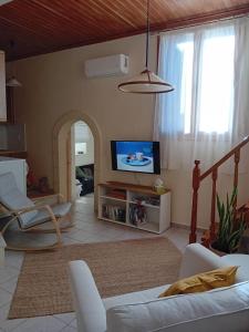 a living room with a flat screen tv and a couch at Bezari pool villa in Metochia Fratzeskiana