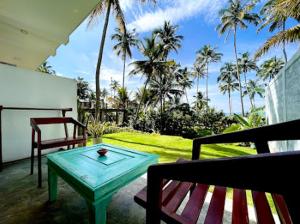um pátio com uma mesa e um banco e palmeiras em Villa LA Kurumba em Ambalangoda