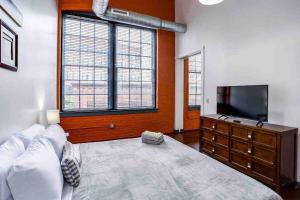 a bedroom with a large bed and a flat screen tv at NY Style Centric Loft with King Bed by Park av in Rochester