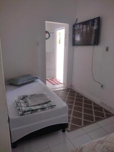 1 dormitorio con 1 cama y TV en la pared en Casa da Mila en Porto Seguro