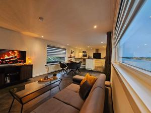een woonkamer met een bank en een groot raam bij Luxe woonboot in de natuur evt met console bootje! in Leeuwarden