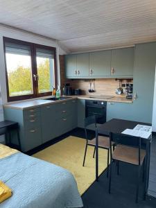 uma cozinha com armários azuis, uma mesa e uma cama em Stúdió Nagymaros em Nagymaros