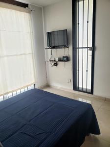 1 dormitorio con 1 cama azul y TV en Casa Santa María en Pénjamo