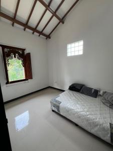 Cette chambre blanche dispose d'un lit et d'une fenêtre. dans l'établissement Villa Kaki Bukit Ciwidey, à Cisondari