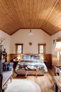 a bedroom with a bed and a wooden ceiling at Hideaway Farmlet Romantic Cottage with Miniature Goats in Penguin