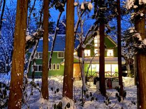 a green house in the snow with trees at Snow Horizon in Hakuba