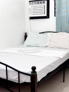 Cette chambre comprend un lit avec des draps blancs et un ventilateur. dans l'établissement Calapan Transient House L12, à Calapan