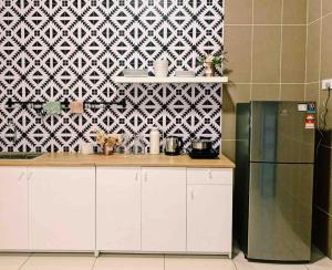 a kitchen with white cabinets and a black and white wall at Paradise Villa Kempas Utama in Skudai