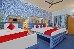 two beds in a room with blue and red at OYO Flagship Meenu Inn in Jaipur