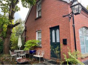 Self Contained Coach House in Leafy South Belfast the location is not accurate في بلفاست: منزل من الطوب الأحمر مع طاولة وكراسي