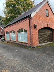 ein rotes Backsteingebäude mit großer Garage in der Unterkunft Self Contained Coach House in Leafy South Belfast the location is not accurate in Belfast