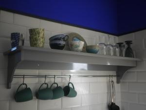 - une étagère dans une cuisine avec des tasses et des ustensiles dans l'établissement Nature, Mer, Golf & Decouvertes..., à Plouha