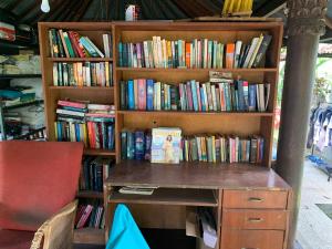 une étagère remplie de livres à côté d'un bureau dans l'établissement Studio Lumbung, à Lovina