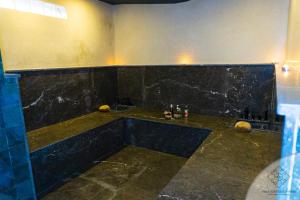 La salle de bains est pourvue d'un lavabo et d'un mur en marbre noir. dans l'établissement Villa Boutique Amani, à Marrakech