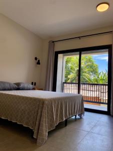 ein Schlafzimmer mit einem Bett und einem großen Fenster in der Unterkunft Villa Julião in Ilhabela