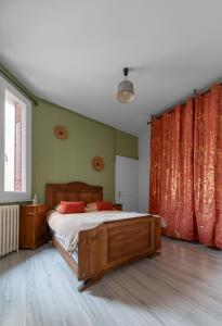 - une chambre avec un lit en bois et des rideaux rouges dans l'établissement Le Louis B - Appartement calme et lumineux proche Thermes, à Vichy