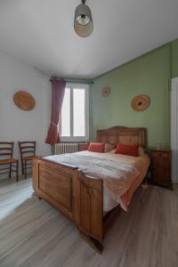 ein Schlafzimmer mit einem Holzbett mit zwei roten Kissen in der Unterkunft Le Louis B - Appartement calme et lumineux proche Thermes in Vichy