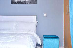 ナイロビにあるAqua Modern Studio Near Ngong Roadのベッドルーム(白いベッド1台、青いスツール付)