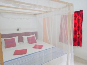 a bedroom with a white bed with red pillows at Arachchi Guest House in Mirissa