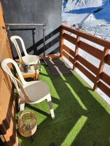 a balcony with two white chairs and grass at La Mongie 6 couchages pied de pistes in La Mongie